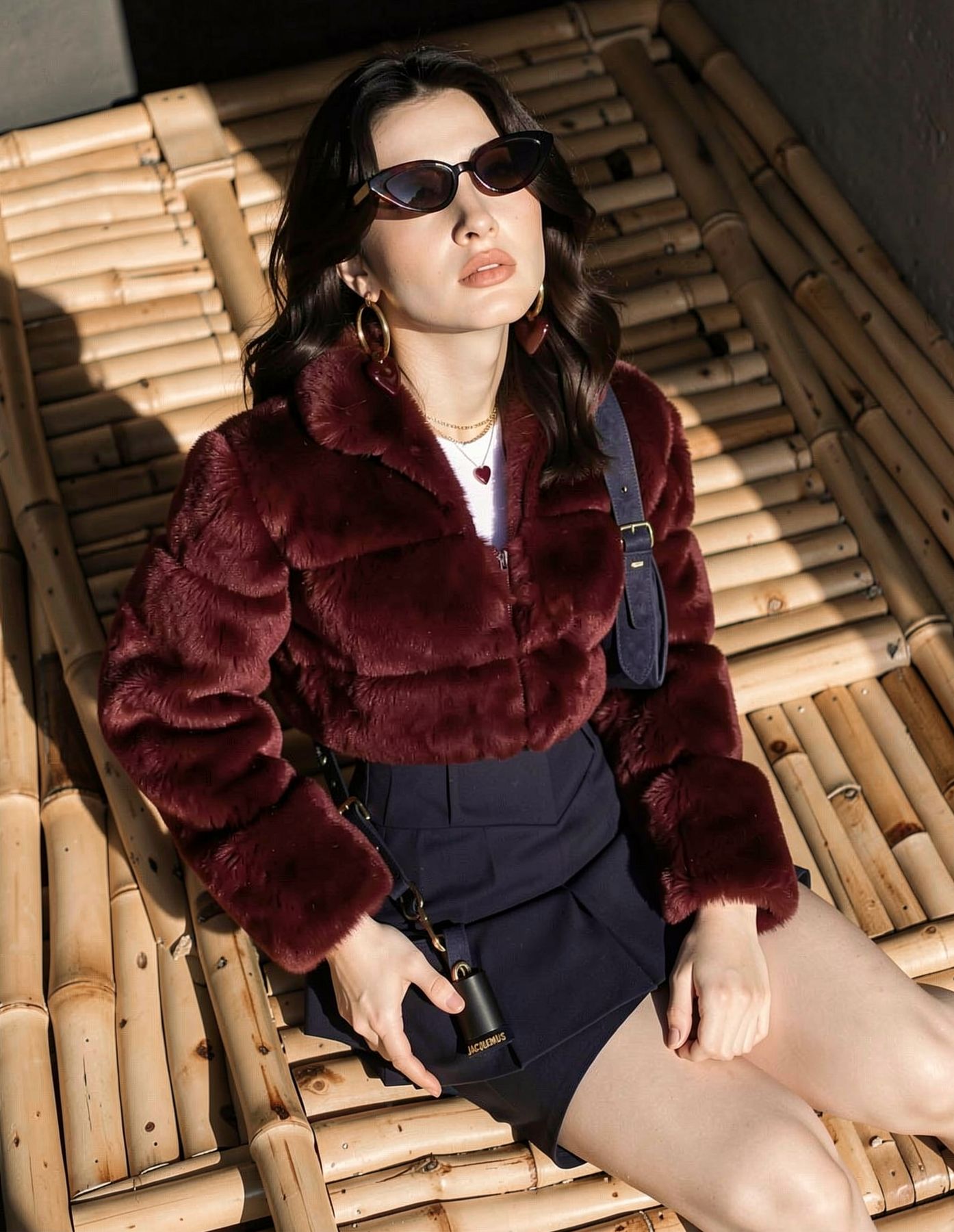 Close-up portrait in a burgundy outfit beside bamboo